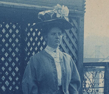 Blue-tinted print of a woman wearing a floral hat, standing in a garden